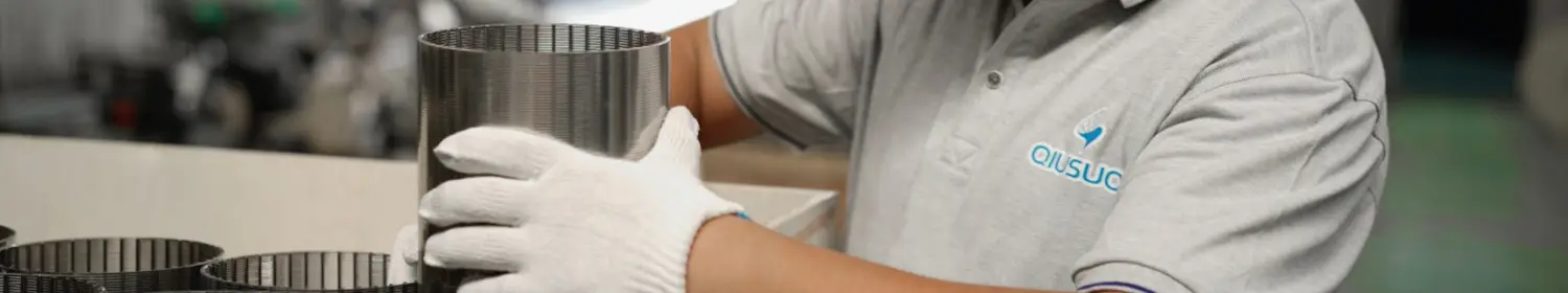 A worker is placing wedge wire screen tubes into wooden cases.