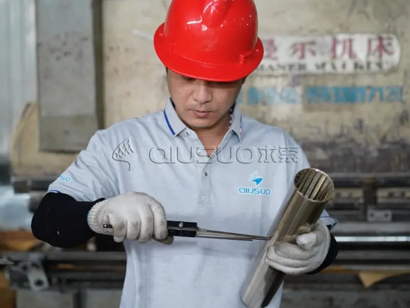 A worker is measuring the wedge wire tube slot size.