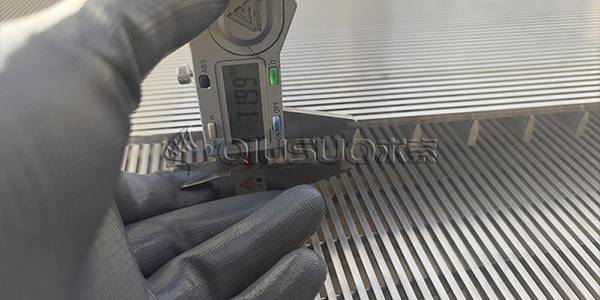 A hand is measuring support bar height of wedge wire screen panel with caliper.